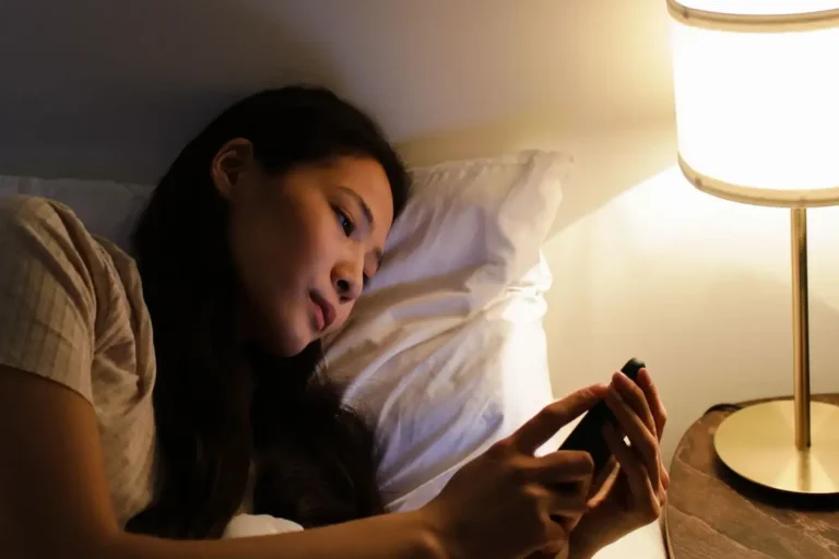 Femme écrivant un message sur son téléphone le soir