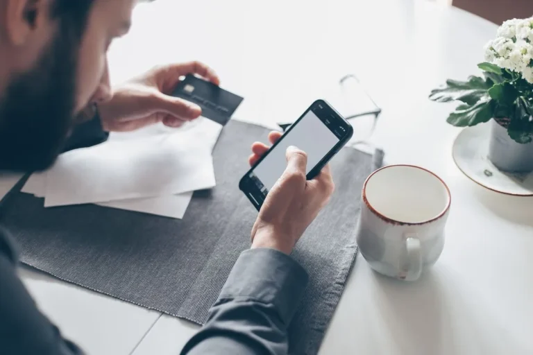 Personne tenant une carte bancaire et un smartphone pour un paiement en ligne