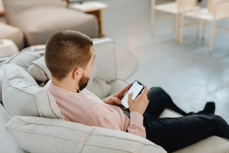 Homme assis dans un canapé consultant son smartphone